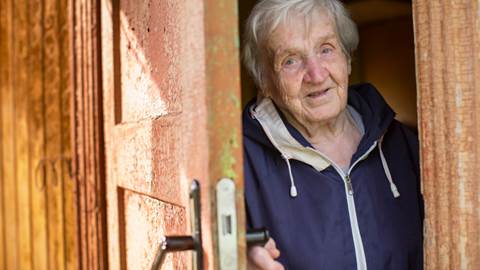 Äldre kvinna öppnar en ytterdörr