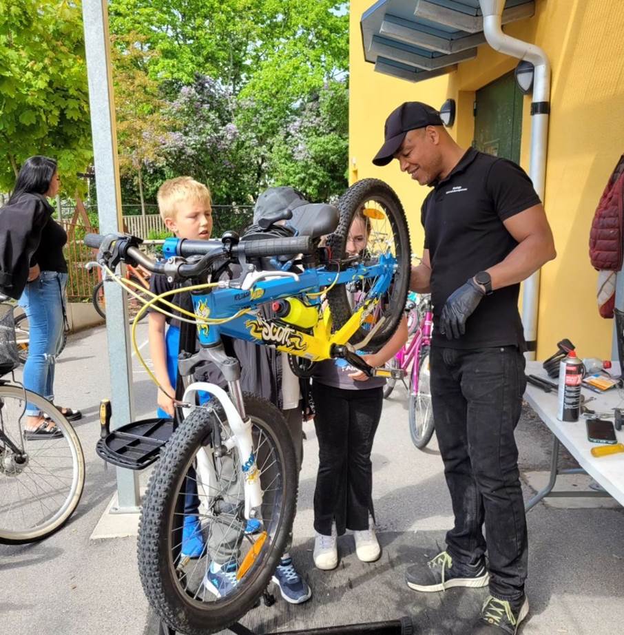 Cykelreparatör Latif Bazzine och två barn servar en cykel.